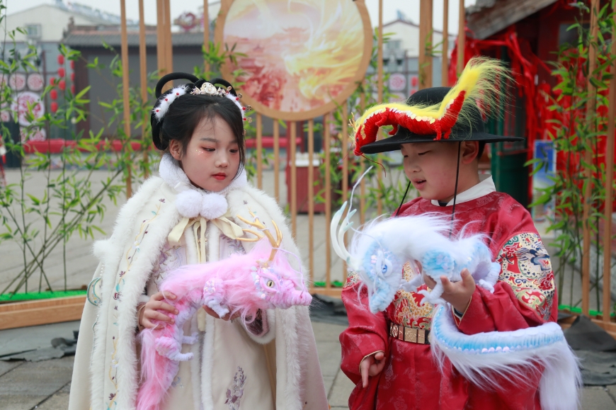 在洛邑古城景区，两位小朋友展示龙形配饰。人民网记者 慎志远摄